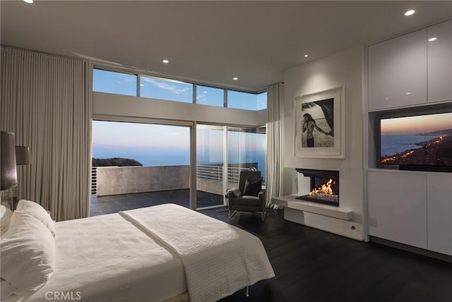 bedroom with access to outside, recessed lighting, wood finished floors, and a warm lit fireplace