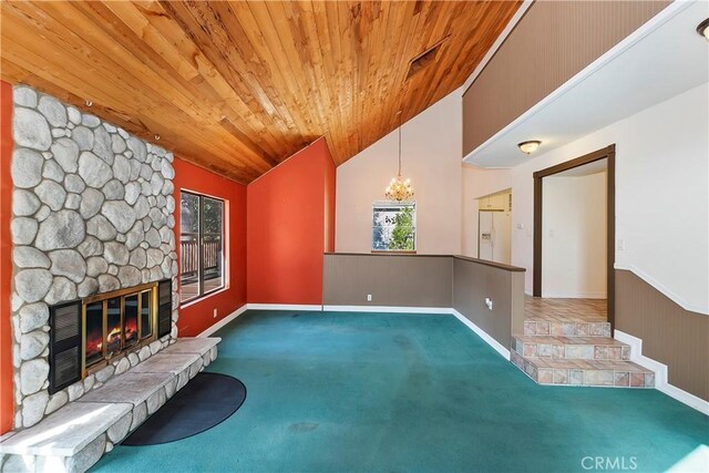 unfurnished living room featuring carpet, a wainscoted wall, lofted ceiling, a stone fireplace, and wood ceiling