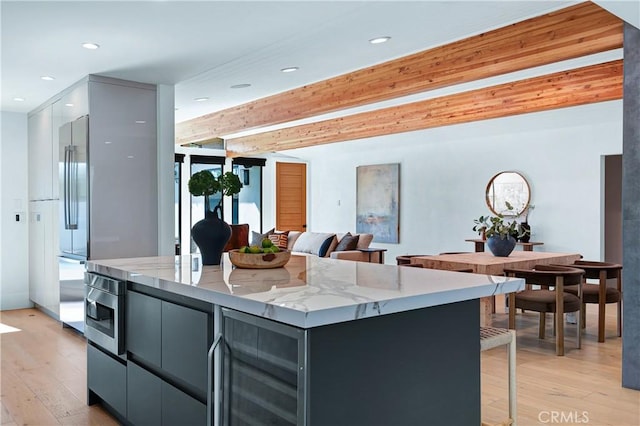 kitchen featuring wine cooler, light wood-style floors, appliances with stainless steel finishes, light stone countertops, and modern cabinets