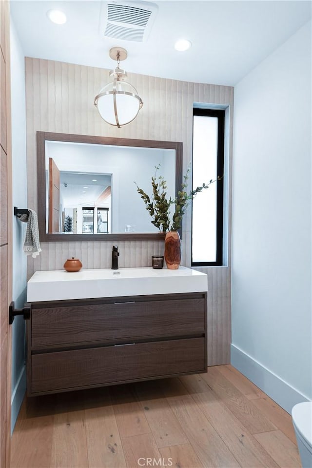 bathroom with visible vents, baseboards, toilet, wood-type flooring, and vanity