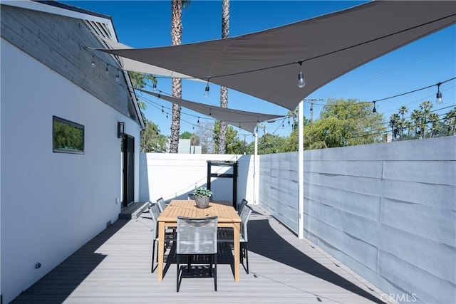 wooden terrace with outdoor dining space and a fenced backyard