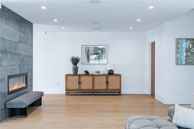 living room with light wood-style floors, a tiled fireplace, and recessed lighting