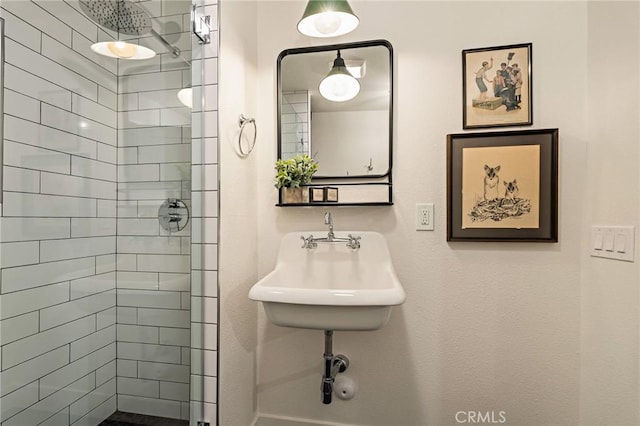 bathroom with tiled shower and a sink