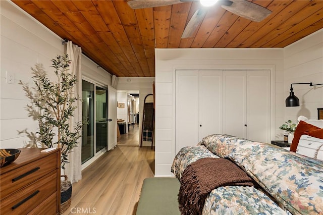 bedroom with light wood-style floors, wooden ceiling, and a closet