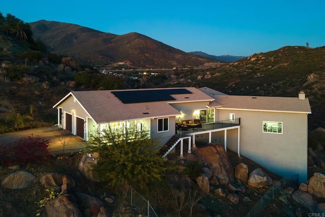 rear view of house with stairway, a chimney, a mountain view, and stucco siding