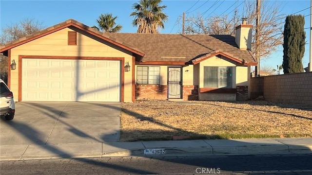 view of front of home featuring a chimney, stucco siding, an attached garage, fence, and driveway