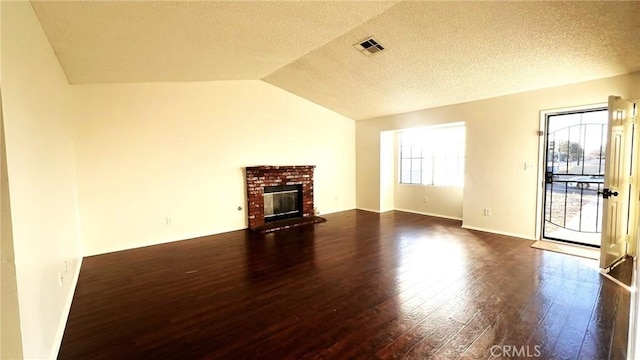 unfurnished living room with dark wood-style floors, a fireplace, visible vents, vaulted ceiling, and a textured ceiling