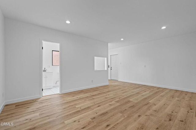 empty room with baseboards, light wood-type flooring, and recessed lighting