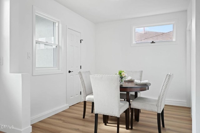 dining area with light wood-type flooring and baseboards