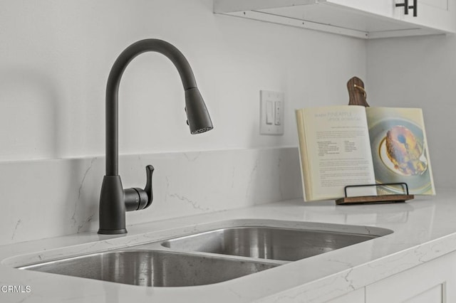 room details featuring light stone countertops, white cabinetry, and a sink