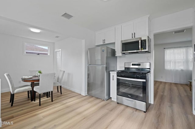 kitchen featuring visible vents, white cabinets, baseboards, stainless steel appliances, and light wood-type flooring