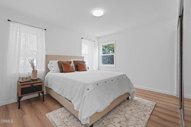 bedroom featuring light wood finished floors and baseboards