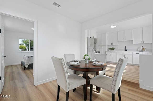 dining area with light wood-style flooring, visible vents, and baseboards