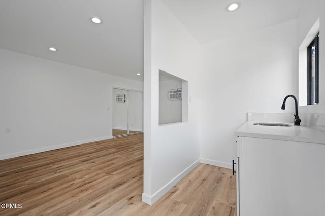 washroom with baseboards, a sink, light wood-style flooring, and recessed lighting