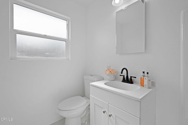 half bathroom with toilet, baseboards, and vanity