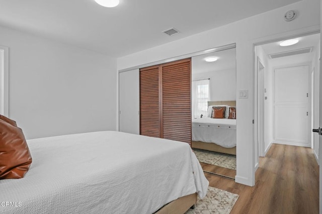 bedroom featuring a closet, visible vents, and wood finished floors