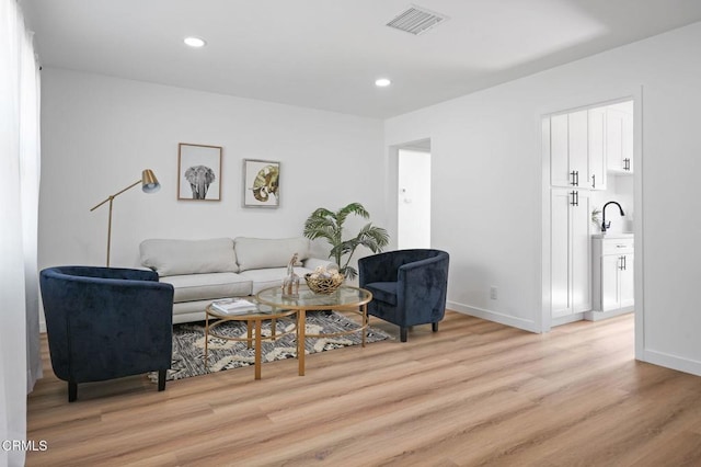 living area with light wood-type flooring, baseboards, visible vents, and recessed lighting