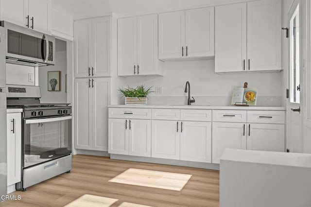 kitchen featuring light countertops, appliances with stainless steel finishes, a sink, and white cabinets