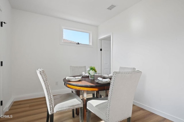 dining area featuring visible vents, baseboards, and wood finished floors