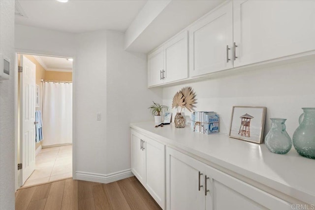 bar with light wood-style floors, crown molding, and baseboards