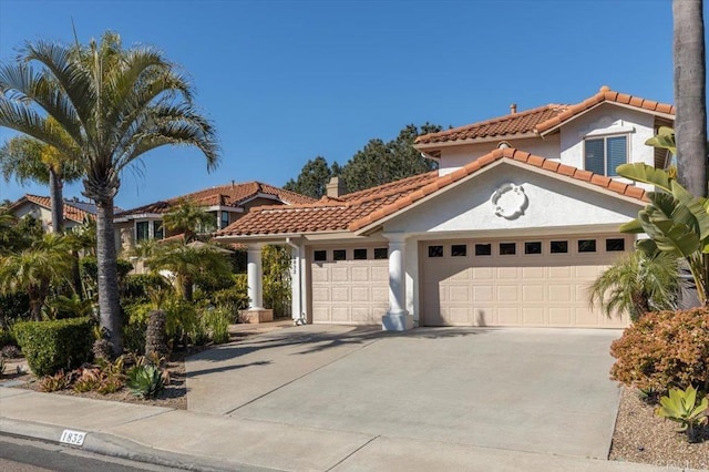 mediterranean / spanish home with driveway, an attached garage, a tile roof, and stucco siding