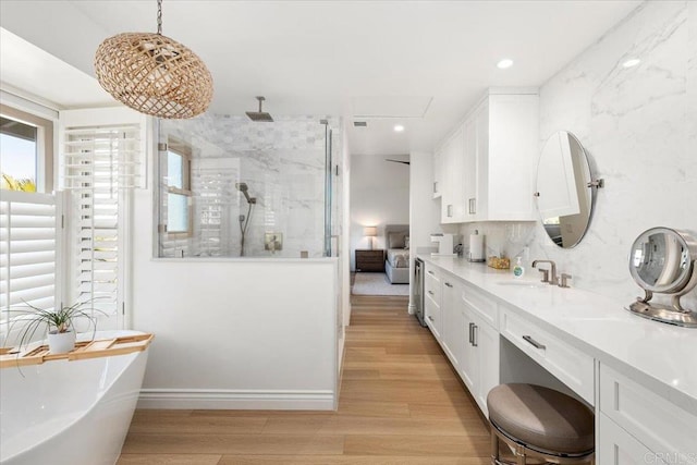 bathroom featuring recessed lighting, a freestanding bath, a shower stall, vanity, and wood finished floors