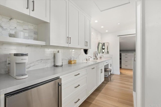 kitchen with open shelves, tasteful backsplash, light countertops, light wood-style flooring, and white cabinets