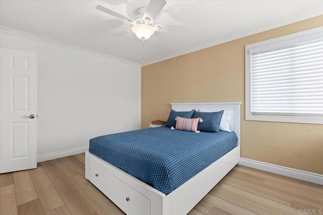 bedroom with a ceiling fan, crown molding, baseboards, and wood finished floors