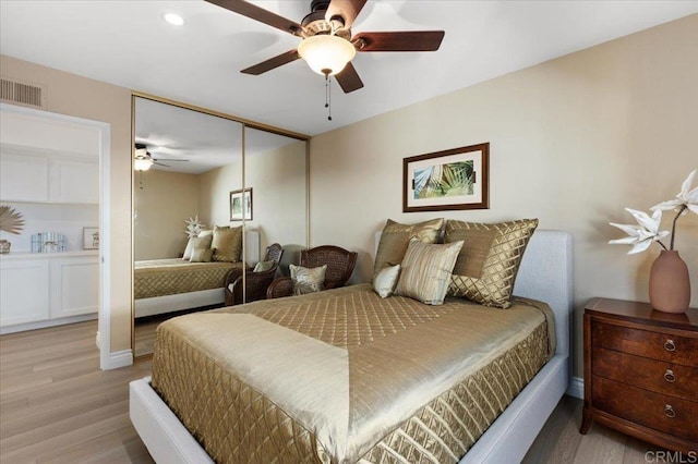 bedroom featuring light wood-style flooring, a closet, visible vents, and a ceiling fan