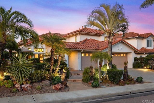 view of front of house featuring an attached garage, stucco siding, driveway, and a tiled roof