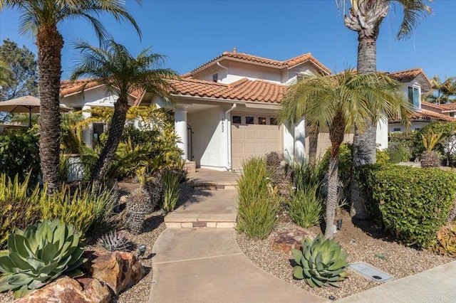 mediterranean / spanish-style house featuring a garage, stucco siding, and a tiled roof