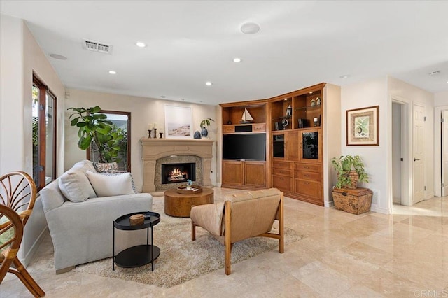 living room with a high end fireplace, visible vents, baseboards, and recessed lighting