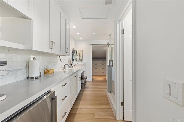 kitchen featuring light wood-style floors, white cabinets, light countertops, and a barn door