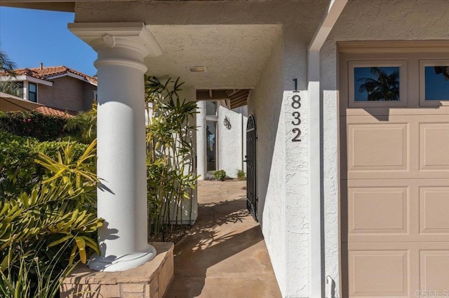 entrance to property with a garage and stucco siding