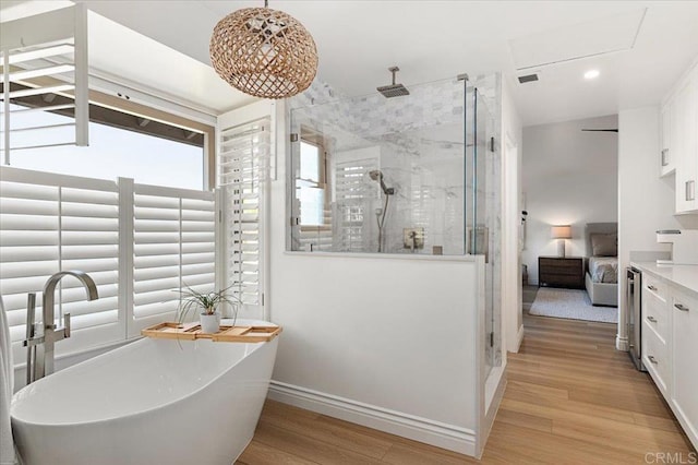 bathroom featuring a stall shower, a freestanding tub, wood finished floors, and vanity