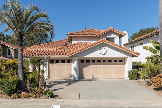 mediterranean / spanish-style house with a garage, stucco siding, driveway, and a tiled roof