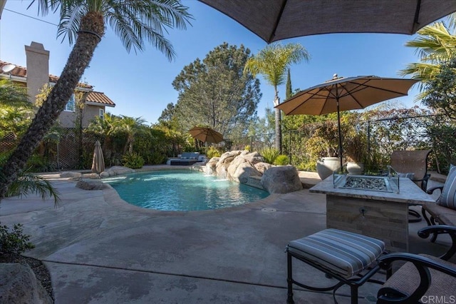 view of swimming pool with a fire pit, a patio, fence, and a fenced in pool