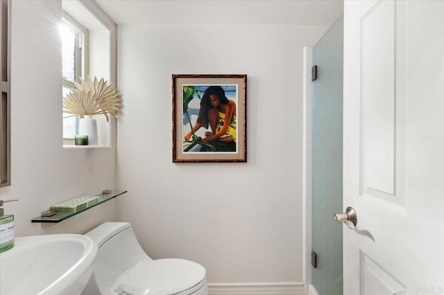 bathroom with toilet, baseboards, and a sink