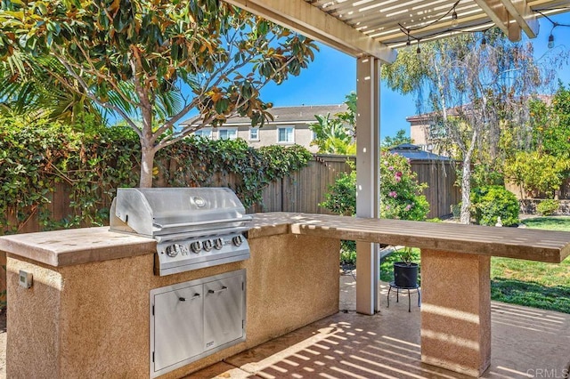 view of patio / terrace featuring fence, an outdoor kitchen, area for grilling, and a pergola