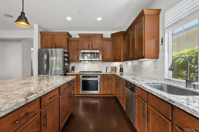 kitchen featuring light stone counters, dark wood-style flooring, stainless steel appliances, backsplash, and a sink