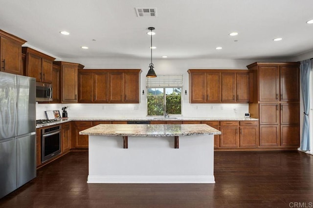 kitchen with dark wood-style floors, stainless steel appliances, visible vents, and a center island