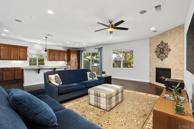 living room with baseboards, visible vents, dark wood-type flooring, a fireplace, and recessed lighting