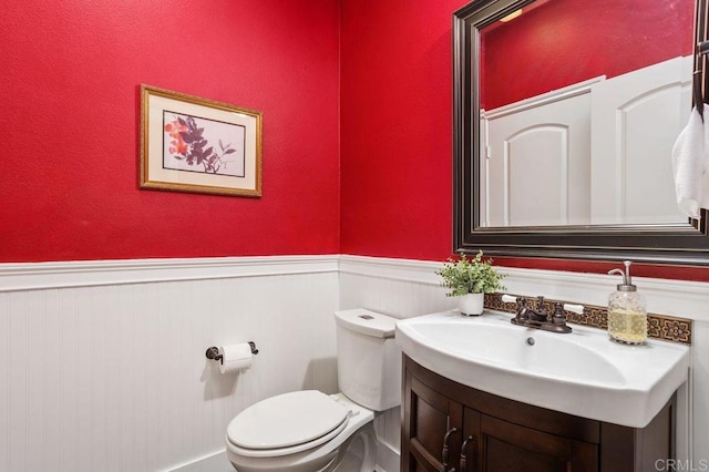 bathroom with a wainscoted wall, vanity, and toilet