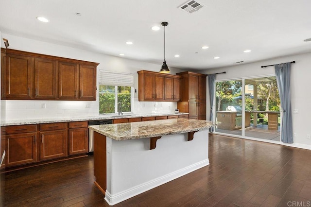 kitchen with dark wood-type flooring, visible vents, stainless steel dishwasher, backsplash, and light stone countertops