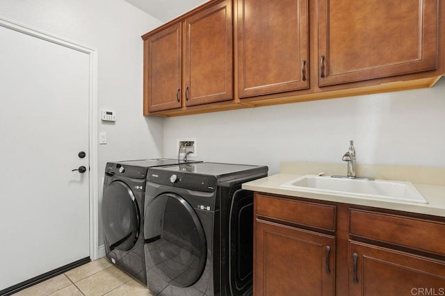 laundry room with a sink, light tile patterned flooring, washing machine and dryer, and cabinet space