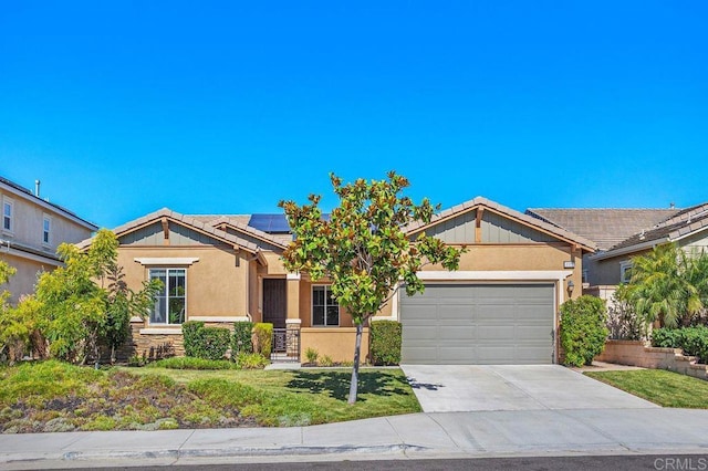 view of front of home with a garage, solar panels, stone siding, driveway, and stucco siding