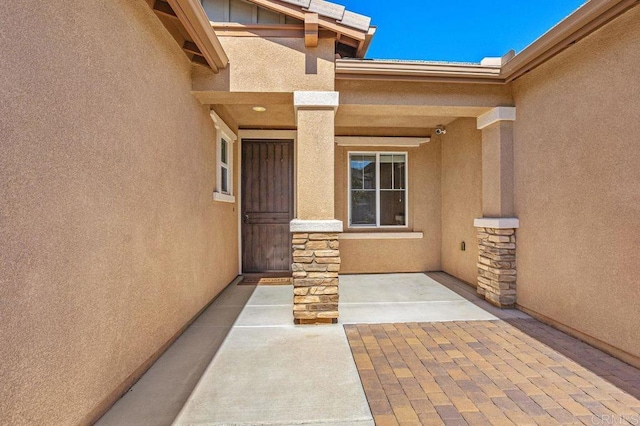 doorway to property with stone siding and stucco siding