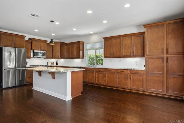 kitchen with stainless steel appliances, visible vents, dark wood finished floors, and a breakfast bar area