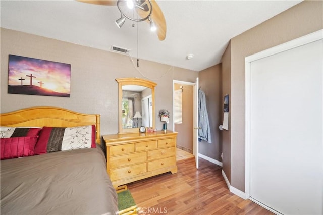 bedroom featuring a ceiling fan, wood finished floors, visible vents, and baseboards