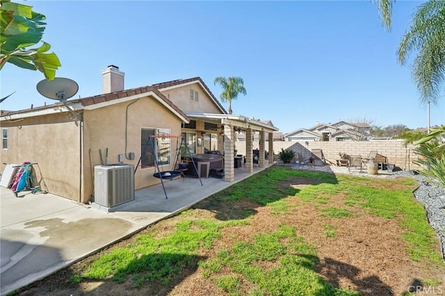 rear view of property with a patio, a fenced backyard, cooling unit, stucco siding, and a chimney